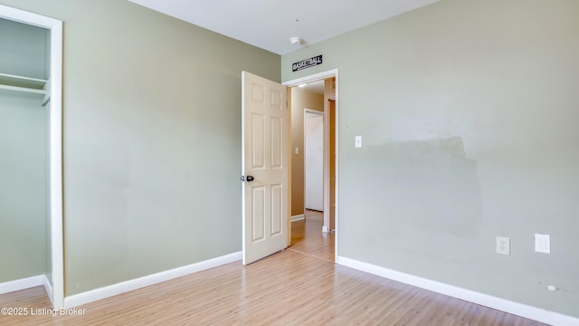 unfurnished bedroom with light wood-type flooring, baseboards, and a closet