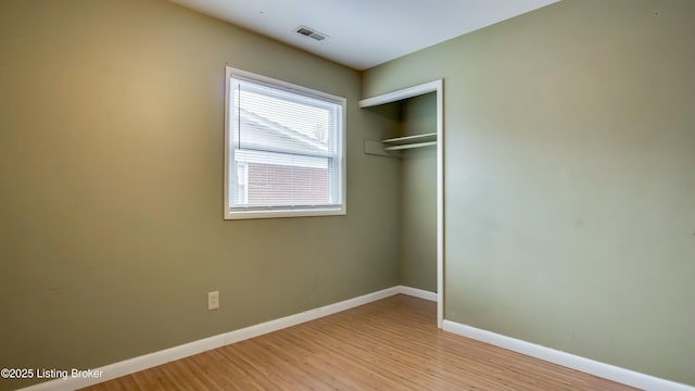 unfurnished bedroom featuring light wood-style flooring, visible vents, baseboards, and a closet