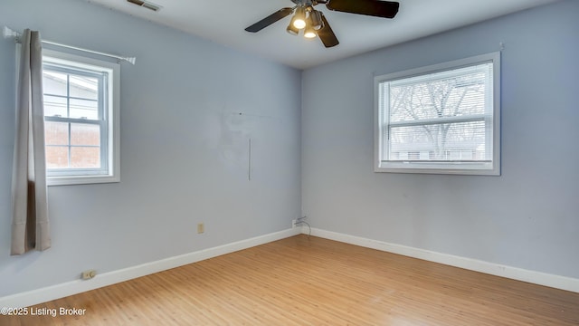 unfurnished room featuring light wood-style floors, visible vents, baseboards, and a ceiling fan