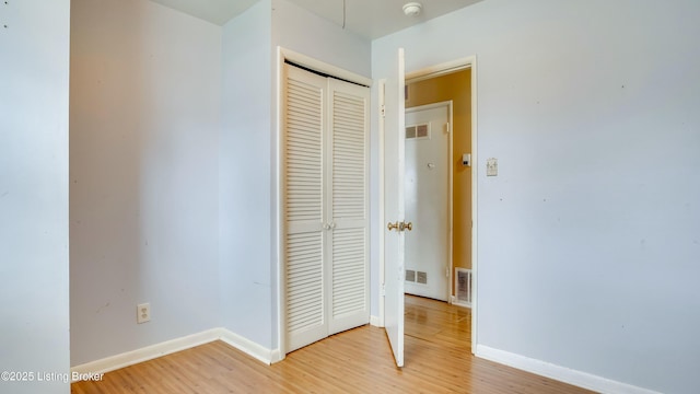 unfurnished bedroom featuring a closet, visible vents, baseboards, and light wood finished floors