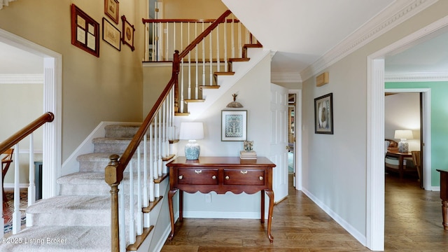 stairs with crown molding, baseboards, and wood finished floors