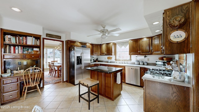 kitchen with ceiling fan, light tile patterned floors, stainless steel appliances, a kitchen island, and built in desk