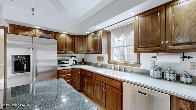 kitchen featuring recessed lighting, a toaster, stainless steel appliances, a sink, and dark stone countertops