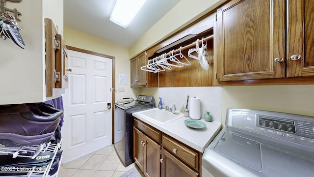 washroom with light tile patterned floors, a sink, cabinet space, and washer and dryer