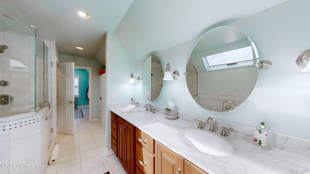 bathroom with double vanity, a stall shower, vaulted ceiling with skylight, and a sink