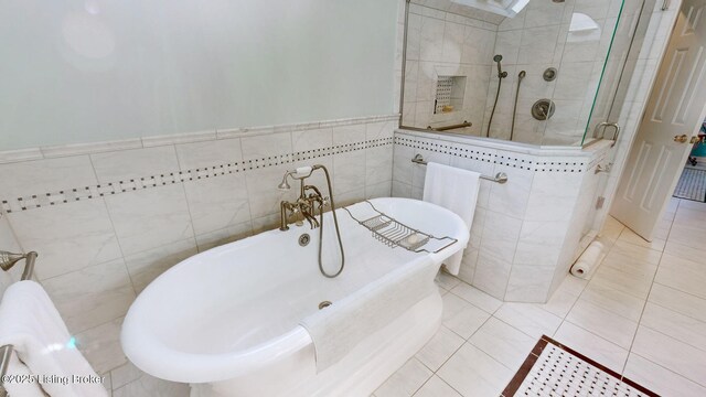 full bathroom featuring a stall shower, a freestanding tub, tile walls, and tile patterned floors