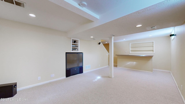 finished below grade area featuring baseboards, visible vents, a textured ceiling, and recessed lighting