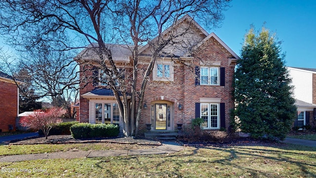 traditional home with a front lawn and brick siding