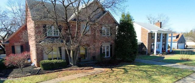 view of front of house with a front lawn, a detached garage, and brick siding