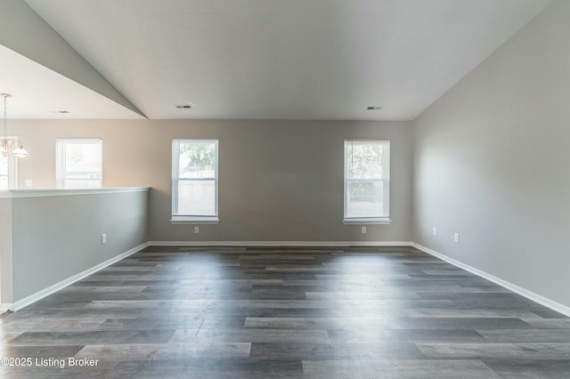 unfurnished room featuring baseboards, visible vents, dark wood-style flooring, vaulted ceiling, and a chandelier