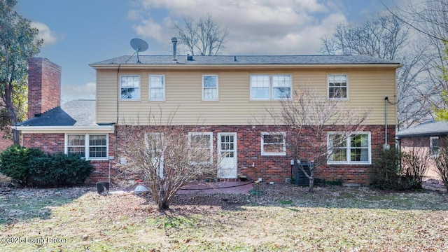 back of property featuring a chimney, a lawn, and brick siding