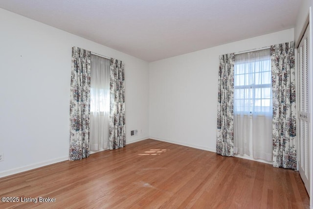 spare room featuring light wood-type flooring and baseboards