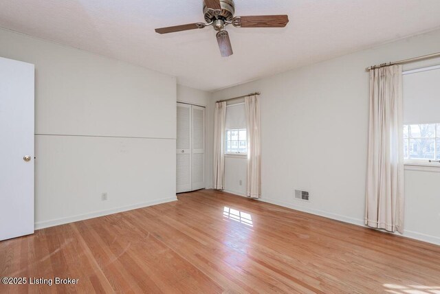 unfurnished bedroom featuring light wood-style floors, multiple windows, and visible vents