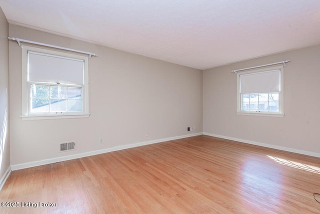 spare room with a wealth of natural light, baseboards, and light wood finished floors