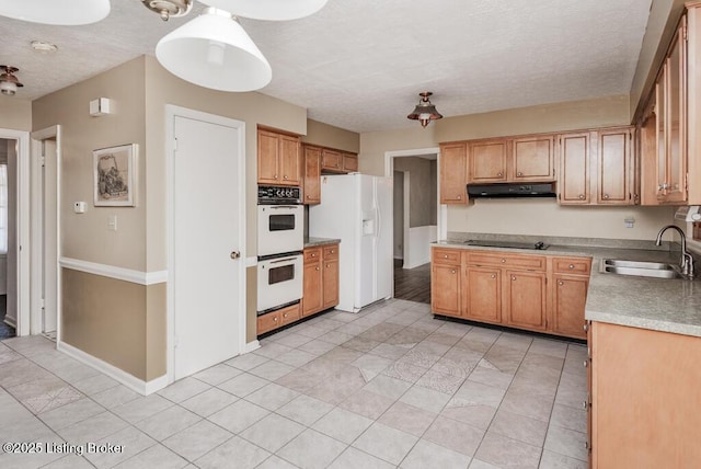 kitchen with a textured ceiling, under cabinet range hood, white appliances, a sink, and baseboards