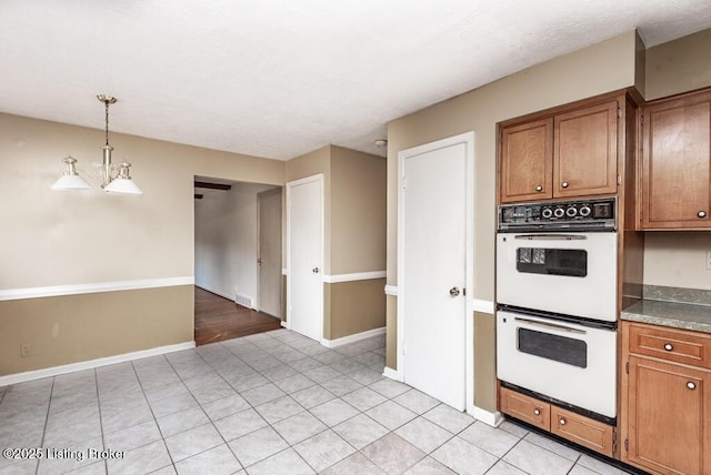 kitchen with baseboards, double oven, brown cabinetry, and pendant lighting