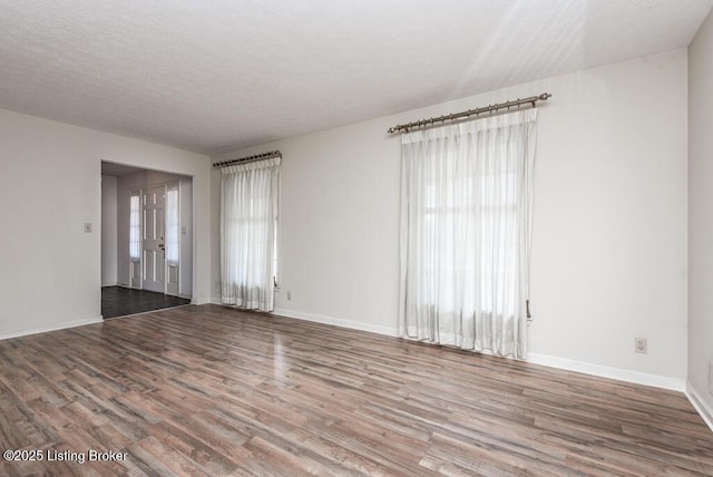 spare room featuring a textured ceiling, baseboards, and wood finished floors