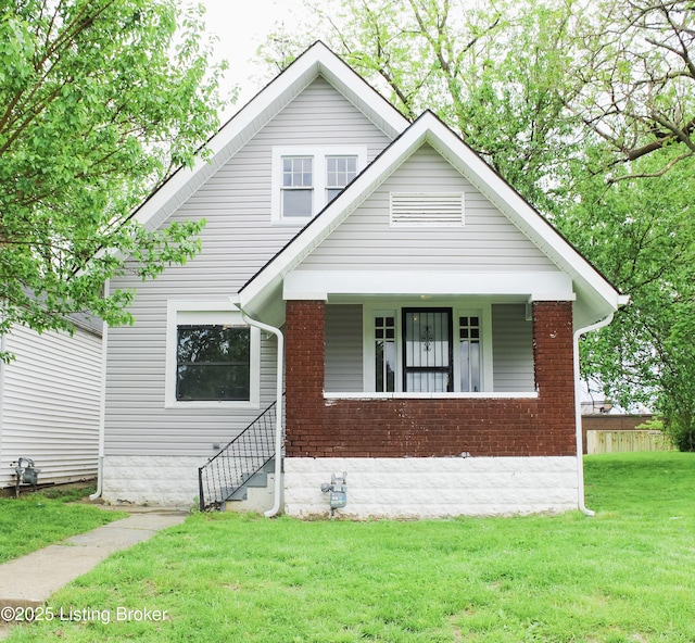 bungalow featuring a front yard and brick siding