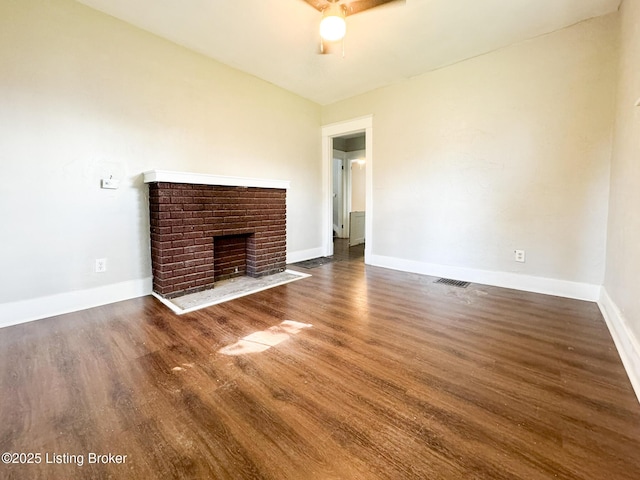 unfurnished living room with a brick fireplace, visible vents, dark wood finished floors, and baseboards