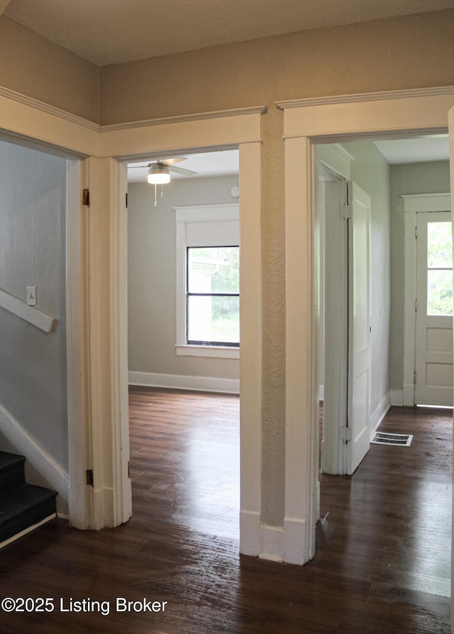 corridor with stairs, dark wood-type flooring, and baseboards