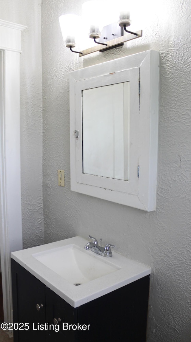 bathroom with a textured wall and vanity