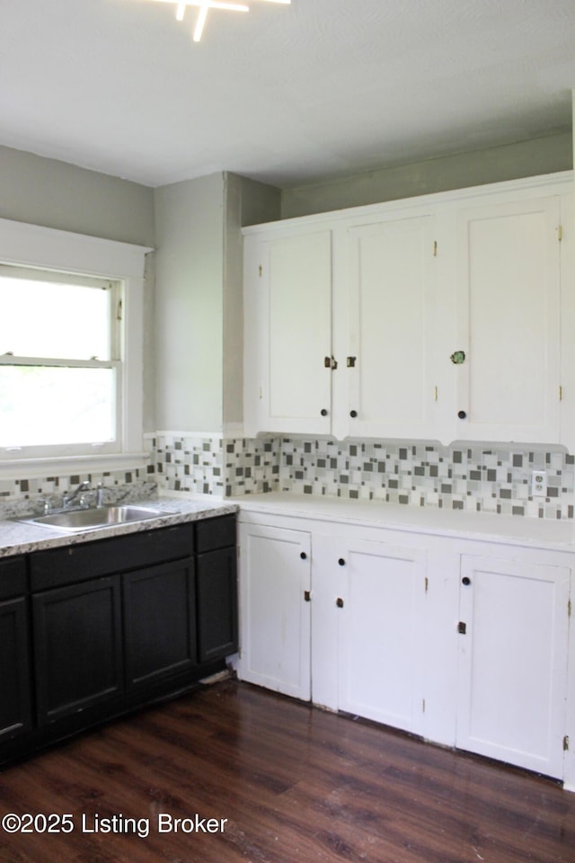 kitchen with a sink, light countertops, backsplash, and white cabinetry