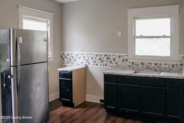 kitchen with dark wood finished floors, dark cabinets, freestanding refrigerator, light countertops, and a sink