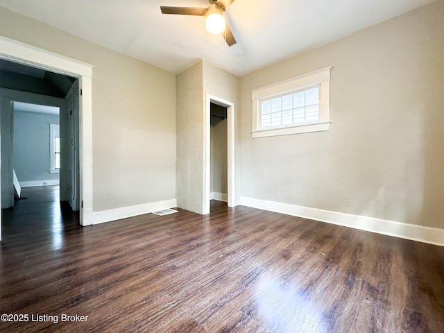 unfurnished bedroom featuring multiple windows, dark wood finished floors, and baseboards