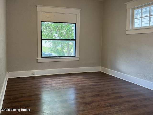 unfurnished room with dark wood-style floors, a textured wall, and baseboards