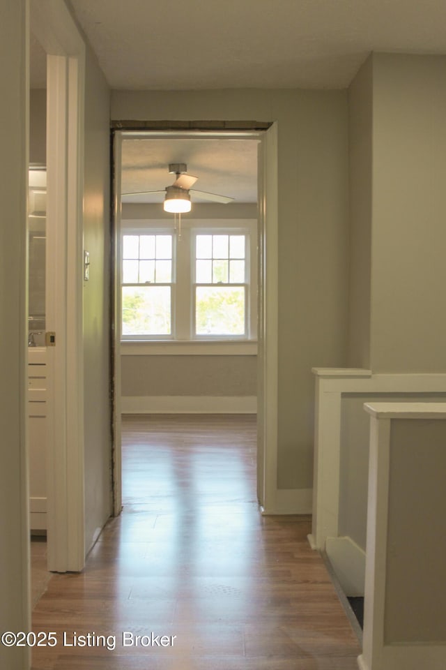 hall with baseboards and wood finished floors