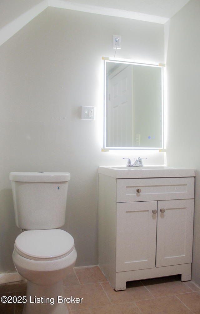 half bath with tile patterned flooring, vanity, and toilet