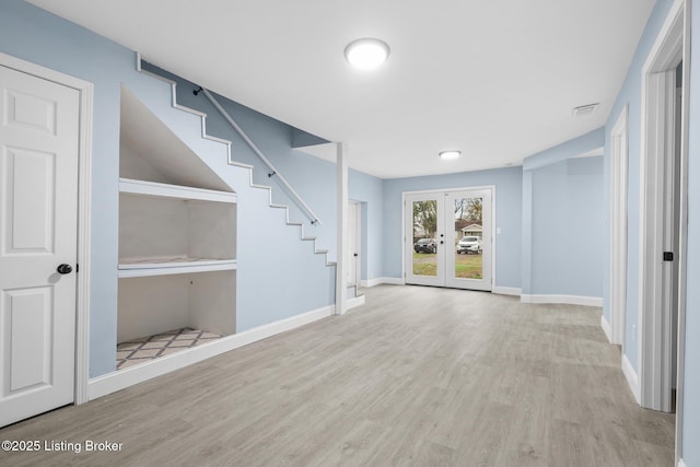 interior space featuring french doors, visible vents, light wood-style flooring, baseboards, and stairs