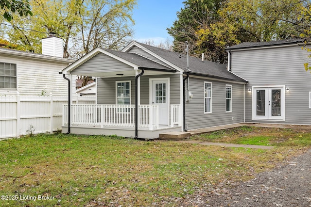 back of house featuring a porch, fence, a yard, french doors, and roof with shingles