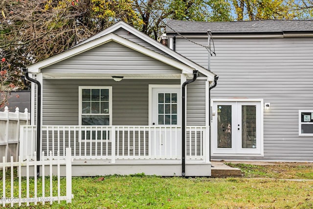 back of property featuring a yard, french doors, a porch, and fence