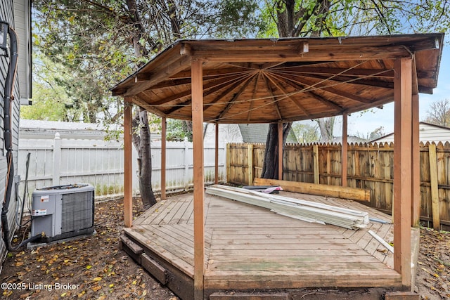 wooden terrace with cooling unit, a fenced backyard, and a gazebo