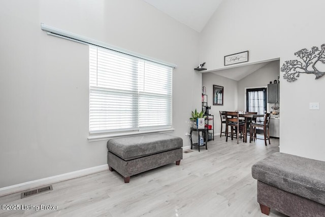 living area with wood finished floors, visible vents, a wealth of natural light, and baseboards