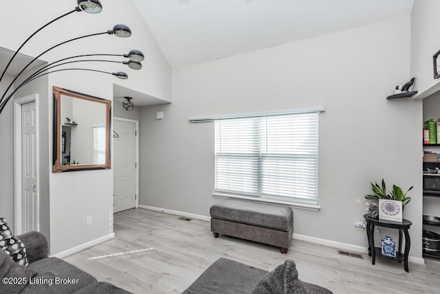 living room featuring vaulted ceiling, wood finished floors, visible vents, and baseboards