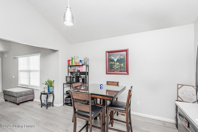 dining space with light wood-type flooring, baseboards, and vaulted ceiling