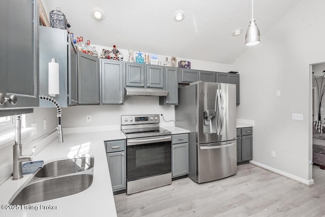 kitchen with under cabinet range hood, light countertops, vaulted ceiling, appliances with stainless steel finishes, and a sink