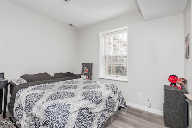 bedroom featuring visible vents, baseboards, and wood finished floors