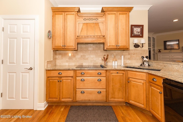 kitchen with a sink, backsplash, black appliances, and light wood finished floors