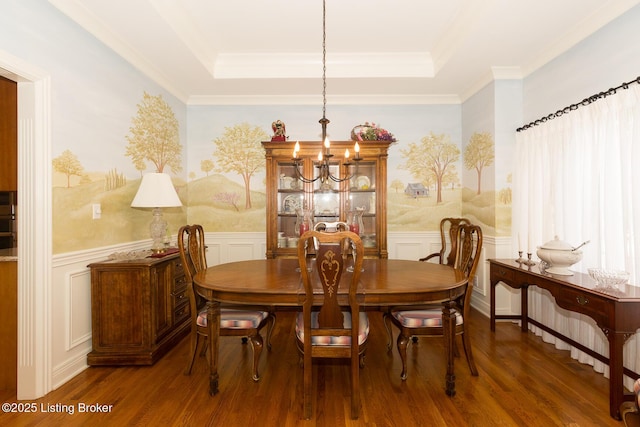 dining area with a chandelier, a tray ceiling, ornamental molding, wainscoting, and wood finished floors