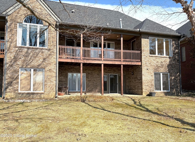 back of property with a yard, brick siding, and a shingled roof