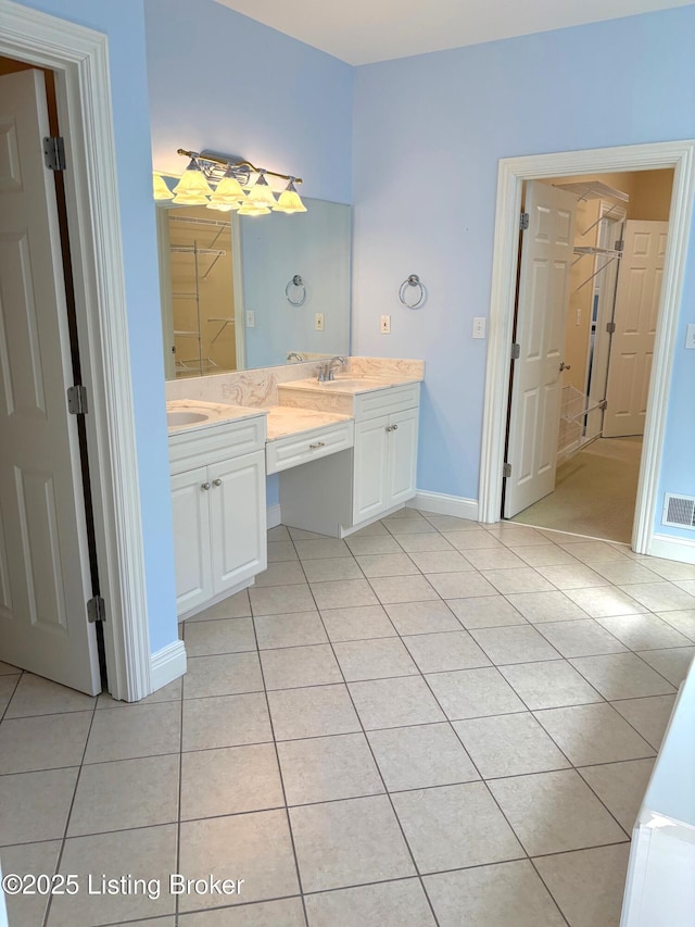 bathroom featuring visible vents, baseboards, double vanity, tile patterned floors, and a sink