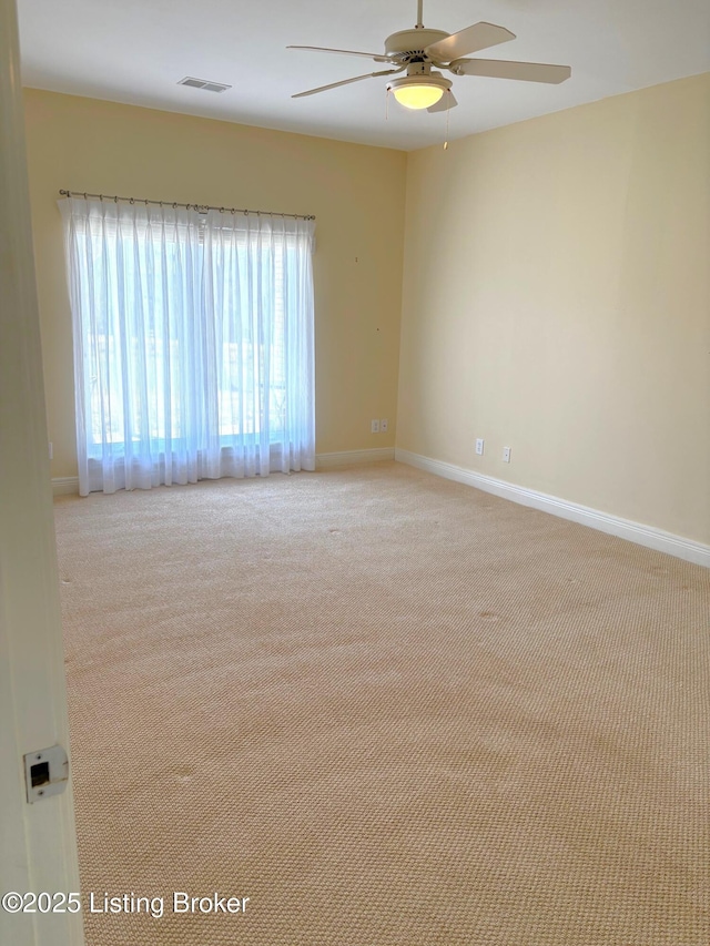 carpeted spare room featuring visible vents, a ceiling fan, and baseboards