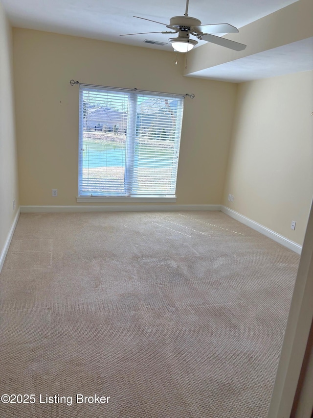 spare room with ceiling fan, visible vents, baseboards, and light carpet