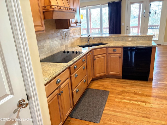 kitchen featuring a sink, light wood-style flooring, black appliances, and a peninsula