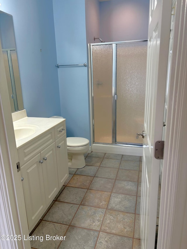 full bathroom with vanity, a shower stall, and toilet