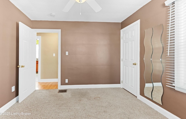 unfurnished bedroom featuring light carpet, ceiling fan, visible vents, and baseboards