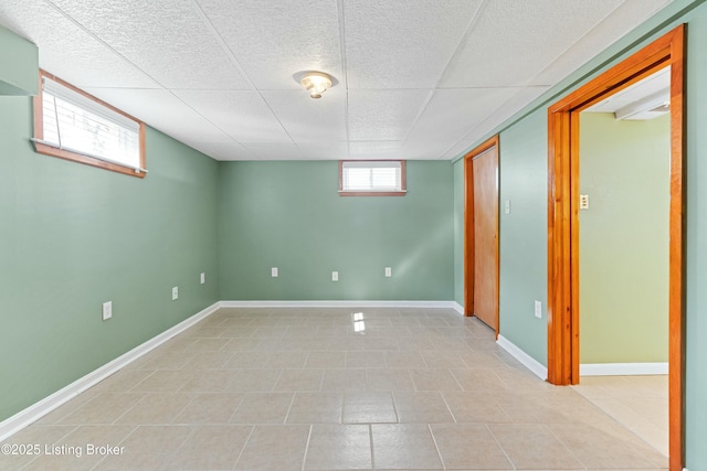 basement featuring a drop ceiling and baseboards